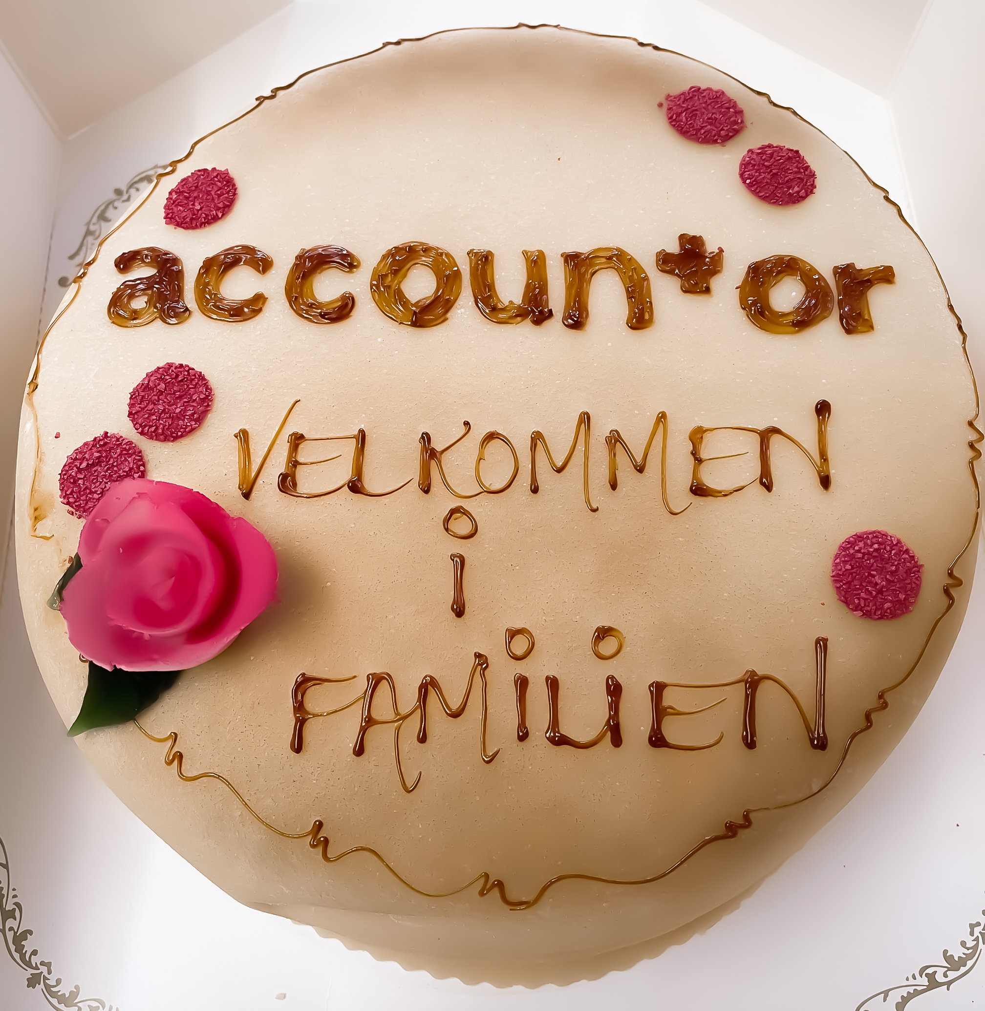 Marsipankake med skrift og en rød/rosa rose: Accountor - velkommen til familien