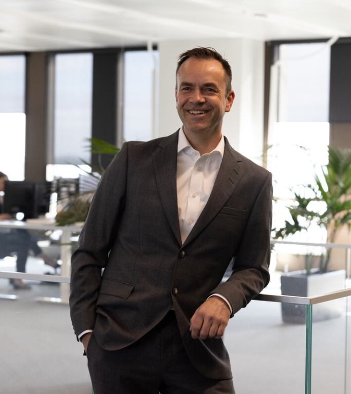 Man som smiler lener seg mot rekkverk