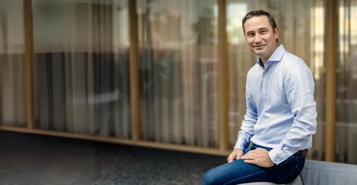 Mann som sitter på en sofakant i et åpent landskap 