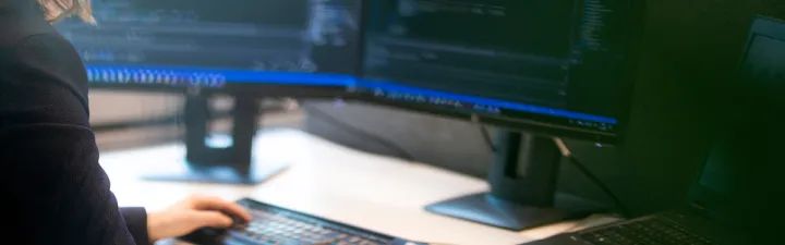 Dame foran pc skjermen som koder 