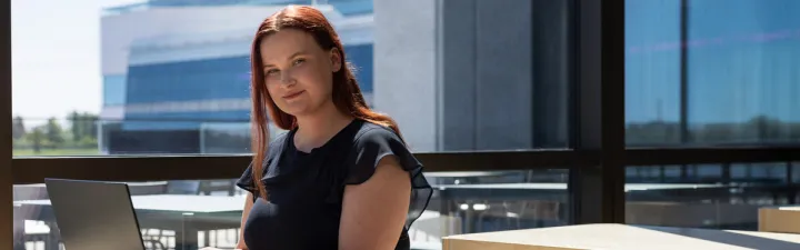 Kvinne i sola som sitter på pcen 